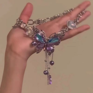 Collier papillon tenu à la main avec cristaux violets et longues franges en métal