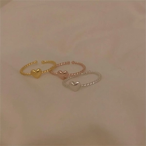 Detailed view of three stackable heart rings in gold, silver, and rose gold finishes