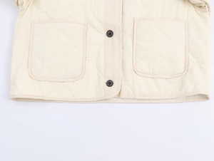 Detail of cream quilted jacket featuring large patch pockets and black button closures