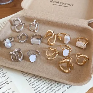 Collection of minimalist gold and silver open rings with pearls in a rustic tray