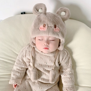 Dettaglio di pagliaccetto in maglia e cappello da orso in peluche per neonato in crema