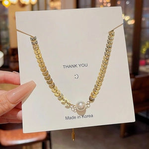 Detail of a French baroque pearl necklace with golden leaf chain on a thank you card