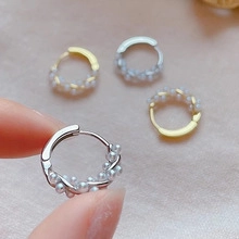 Makro-Detail von handgehaltenen Gold- und Silberperlenohrringen mit Metallwicklung
