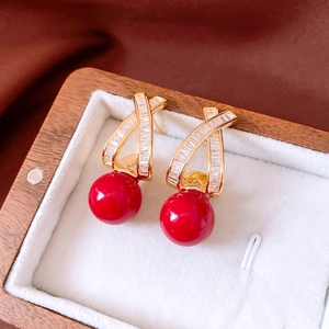 Macro shot of 18k gold plated earrings featuring red round beads and clear zircon details
