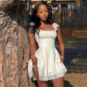 Detail of white mini dress featuring lace trim and square neck with satin fabric texture