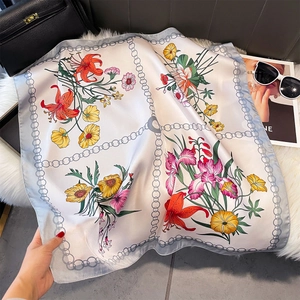 Dettaglio del foulard in seta sintetica con motivi floreali e bordo a catena su pelliccia