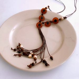 Detailed macro view of bohemian wax rope necklace with resin beads and tassel in a ceramic tray