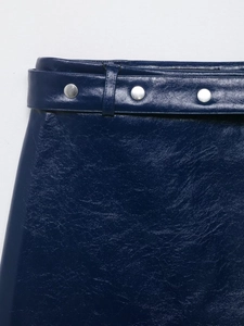 Détail de la taille d'une jupe en cuir bleu foncé avec ceinture et boucles argentées