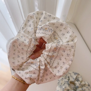 Detailed close-up of white floral cotton scrunchie with blue and yellow flower patterns