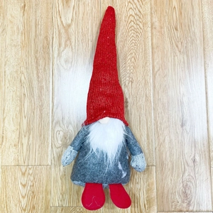 Flat lay of a Christmas gnome with red knit hat and white beard on wooden floor