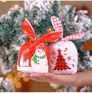 Close-up of festive Christmas gift bags with rabbit ear ties featuring snowman and tree patterns