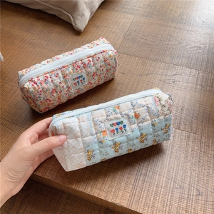 Close-up of quilted floral pencil cases featuring soft cotton fabric and zipper details