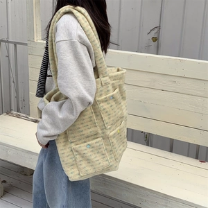 Close-up of yellow plaid plush tote bag with functional pockets and decorative buttons
