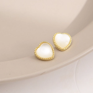 Close-up of golden heart earrings with pearl inlay and delicate beaded texture edges