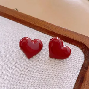 Elegant retro red heart stud earrings with glossy enamel finish on a beige linen tray