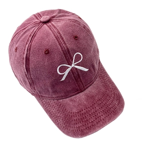 Gros plan de la broderie nœud blanc sur une casquette en jean bordeaux délavé vintage