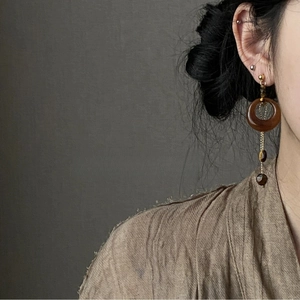 Asymmetric resin tiger eye stone drop earrings with gold chains on model profile