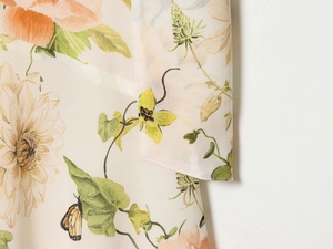 Makroansicht von leichtem Stoff mit lebhaften orangefarbenen Blumen- und Schmetterlingsmustern