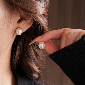 Square pearl stud earrings with gold metal frame worn by a model for a vintage look