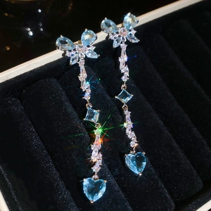 Detailed view of silver tassel earrings with blue butterfly and heart-shaped crystals