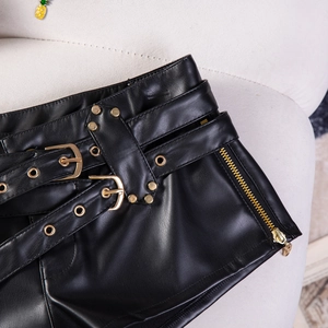Detail von Y2K PU-Ledershorts in Schwarz mit goldenen Schnallen und Reißverschlüssen