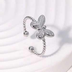 Détail d'une bague papillon argentée sur support ondulé blanc pour bijoux de mode