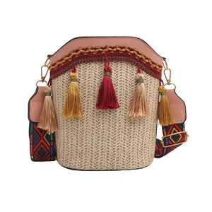 Detail of bohemian straw bucket bag with pink PU trim and colorful geometric strap