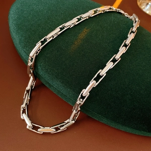 Detail of silver chain link necklace displayed on a green velvet jewelry stand