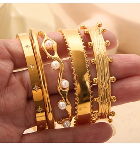 Close-up of five 18k gold plated bracelets set with white faux pearls and small crystals