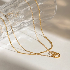 Close-up of golden double-layer stainless steel necklace featuring interlocking rings