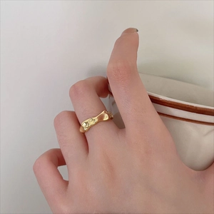 Detailed view of an irregular liquid gold-style ring on finger with high-polish texture