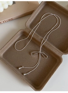 Dettaglio collana con ciondolo a fiocco argento e catena a serpente in confezione