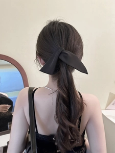 Dettaglio di un fermaglio per capelli a fiocco in raso nero per un look raffinato