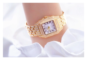 Macro shot of gold-tone square watch with crystals and Roman numerals on a soft fabric