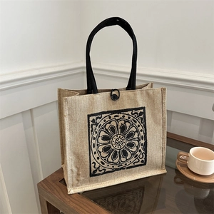 Retro linen tote bag with black ethnic mandala print and woven handles in a lifestyle setting