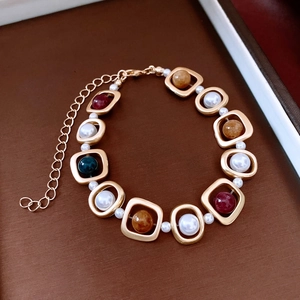 Détail d'un bracelet doré vintage avec maillons évidés, perles et pierres précieuses