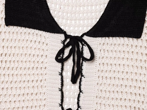 Detail of crochet polo collar with black lace-up tie and cream hollow knit texture