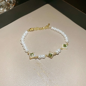 Macro shot of green square zircon accents and white pearls on a vintage gold bracelet