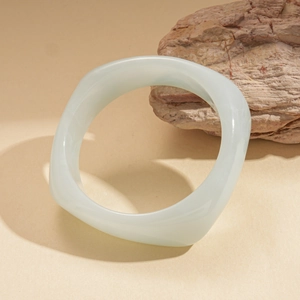 Detailed view of pale green resin geometric bangle on natural stone with warm lighting