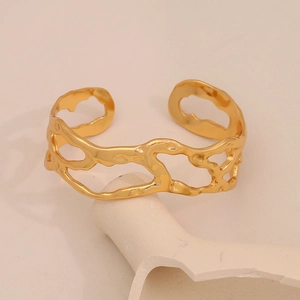 Gros plan sur un bracelet doré ajouré style lave sur support minimaliste