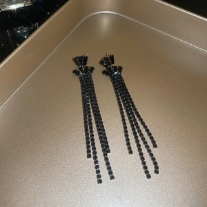 Detail of long black tassel earrings with dark rhinestones on vintage bronze tray