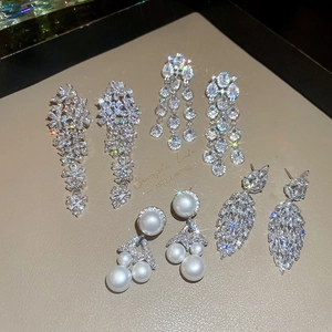Detailed display of five silver needle earrings with cubic zirconia and tassels