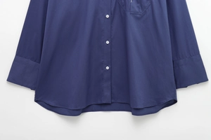 Close-up of a navy blue long sleeve shirt featuring white buttons and a curved hemline