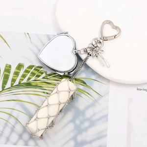 Detail of silver heart-shaped mirror pendant with woven mesh lipstick holder and bow charm