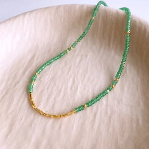 Close-up of green aventurine beads and 18K gold-plated spacers on a ceramic dish