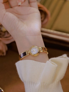 Elegant quartz watch with gold metal and tortoise shell bracelet on a wrist