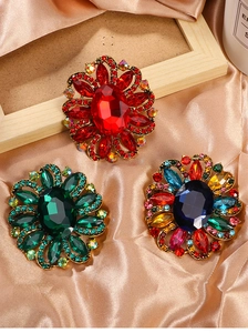 Detailed macro shot of vintage floral brooches with colorful rhinestones on silk