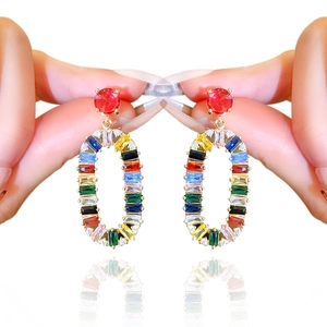 Handheld view of colorful oval crystal drop earrings with red round stone in white background