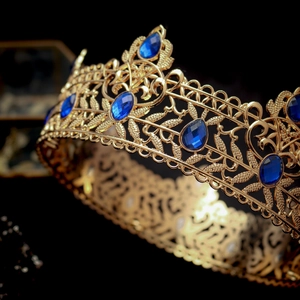 Macro detail of golden baroque crown with intricate filigree and blue gemstones
