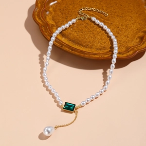 Detail of baroque pearl necklace with emerald green gemstone and gold drop pearl pendant
